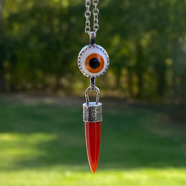 "Since one is love, there is nothing to do but offer love-each offer of love bringing an exponential increase in the quantity of love returned" Melody (Love is in the Earth).
An orange Carnelian point dangles from an orange, 10mm glass "eye". Both are set in textured and oxidized bezels.
Wearing this talisman can open your eyes to your ability to give and receive love of all varieties.
Charm: 2" long x 1/2" wide
Chain: 16" Sterling Silver 2mm patterned and oxidized cable chain with lobster clasp