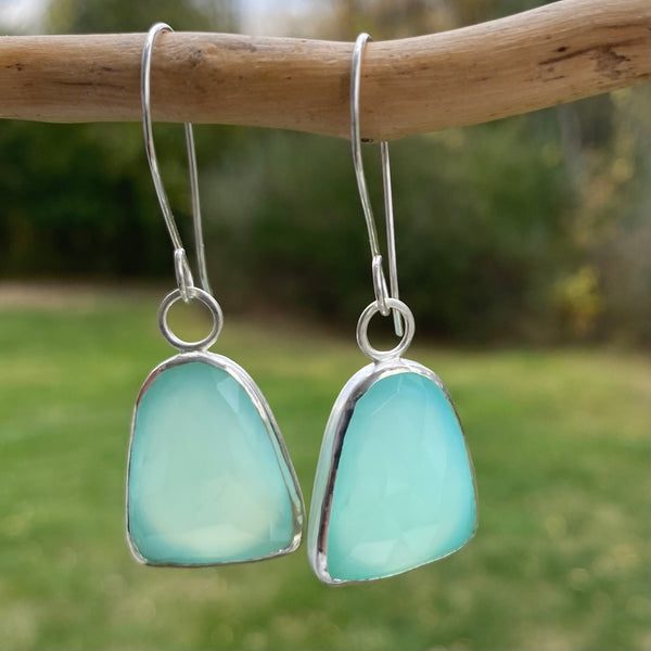 Wear these beautiful, brightly colored aqua earrings when you need the diplomacy Chalcedony can "bring to the tip of your tongue" (Tiny Rituals).  I'm thinking anytime but maybe family gatherings?  
Charm:  Rosecut Chalcedony set in Sterling Silver measures 1 1/4" long x 3/4" wide.
Ear Wires:  20gauge Argentium™ .  Total length of of earring with wires is 2 1/4" long.