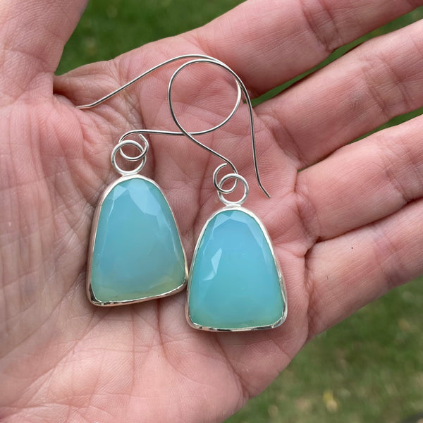 Wear these beautiful, brightly colored aqua earrings when you need the diplomacy Chalcedony can "bring to the tip of your tongue" (Tiny Rituals).  I'm thinking anytime but maybe family gatherings?  
Charm:  Rosecut Chalcedony set in Sterling Silver measures 1 1/4" long x 3/4" wide.
Ear Wires:  20gauge Argentium™ .  Total length of of earring with wires is 2 1/4" long.