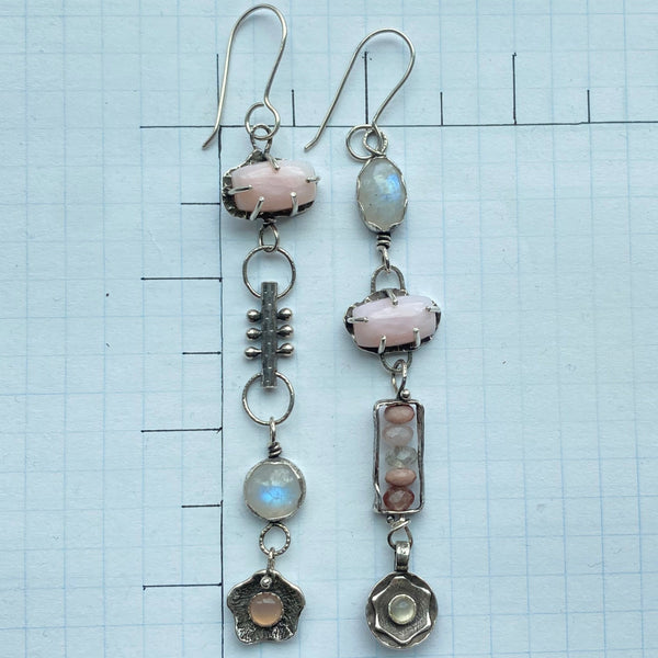 So pretty...eyecatching drama in soft shades of pink and white with rainbow flashes. And like us, these earrings offer so much more than beauty.  They speak to an inner knowing of self and an energy that brings the stars to the soul.
Created with Semiprecious Gemstones and hand crafted Sterling Silver charms.
Two 13.85 x 2.59mm rectangular Pink Opals (prong set)
10mm round Rainbow Moonstone (bezel set)
6mm round Pink Chalcedony (bezel set)
12.5 x 8.7mm oval Rainbow Moonstone (bezel set)
4mm Cat's