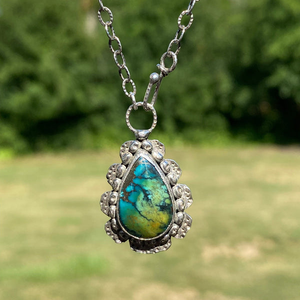 Offering wholeness, the 17 x 10mm pear-shaped Hubei Turquoise has a beautiful color palette of orange, green and blue organic shaped spots on a black background.  It is set in texturized and patinated Sterling Silver.
Charm:  1.25"L x .75"W
Chain:  17" L, 2.8mm oxidized and patterned cable chain