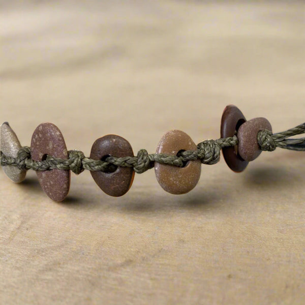 A day at the beach...The smell of suntan lotion.  The warmth of the sun on our skin.  The sounds of waves crashing and children laughing.  Bliss.  Made with hand drilled Lake Michigan beach stones in red-brown colors and khaki colored braided waxed linen cord, wear these bracelets to remind you of all things summer.  The toggle clasp is created from beach stones.  Total length- 8 1/2"  Fits up to 7 3/4" wrist