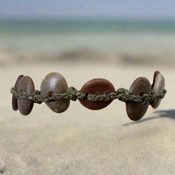 A day at the beach...The smell of suntan lotion.  The warmth of the sun on our skin.  The sounds of waves crashing and children laughing.  Bliss.  Made with hand drilled Lake Michigan beach stones in red-brown colors and khaki colored braided waxed linen cord, wear these bracelets to remind you of all things summer.  The toggle clasp is created from beach stones.  Total length- 8 1/2"  Fits up to 7 3/4" wrist