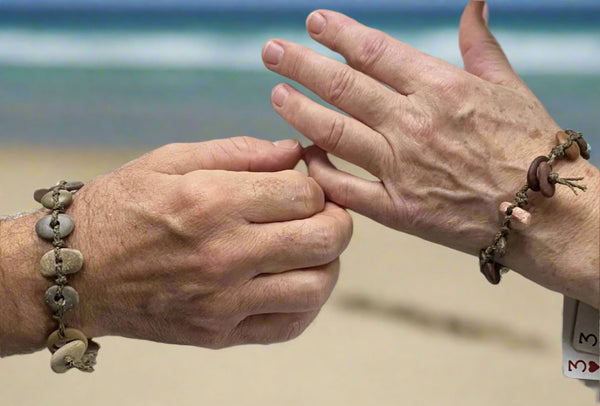 A day at the beach...The smell of suntan lotion.  The warmth of the sun on our skin.  The sounds of waves crashing and children laughing.  Bliss.  Made with hand drilled Lake Michigan beach stones in red-brown colors and khaki colored braided waxed linen cord, wear these bracelets to remind you of all things summer.  The toggle clasp is created from beach stones.  Total length- 8 1/2"  Fits up to 7 3/4" wrist