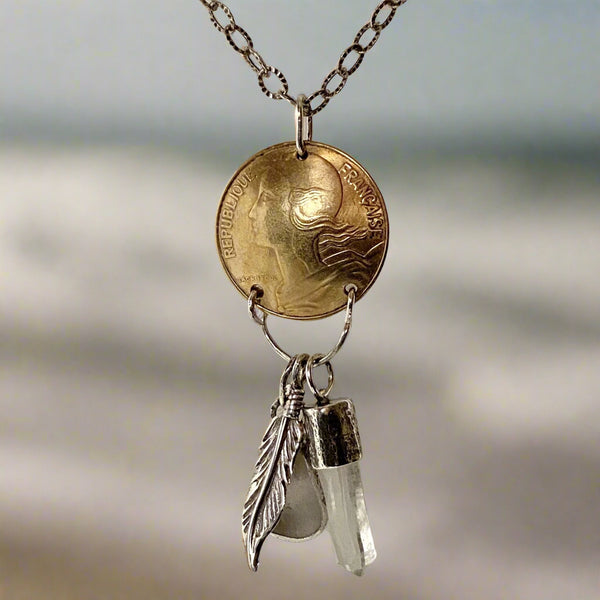 Need to start an Evolution Revolution? Let Marianne, Spirit of the Revolution, ride with you! The vintage French brass coin features the words liberte, egalite and fraternite...liberty, equality, fraternity. She also carries a few charms...a Sterling Silver feather for flight/freedom, Quartz Crystal (known as a master healer) and a bit of beach glass set in Sterling Silver with a heart cut into it.
Charm: 2" long x 3/4" wide
Chain: 18" textured and patinated 2.8mm Sterling Silver