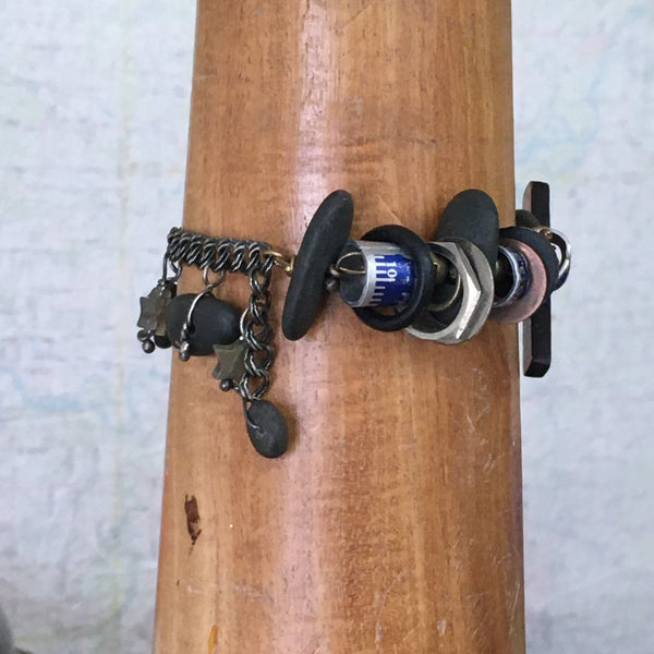 What is it you need to remember?  A birthday?  Why you walked into the kitchen?   This whimsical bracelet uses a vintage ruler and beach stone to create the unique toggle clasp.  Other random miscellany (bits of sewing rulers and hardware store parts) symbolize all the "bits" floating in our heads.  Fancy Jasper stars can remind us to be kind to our forgetful selves!  Sterling Silver double Curb chain.  Size:  8" long x 1 1/2" at the widest part