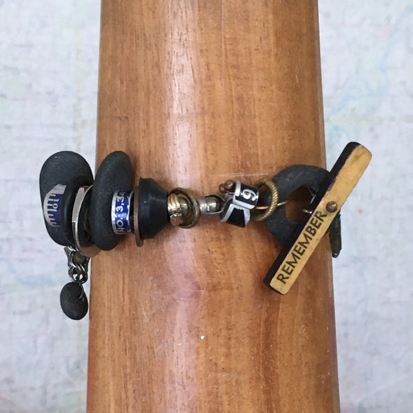 What is it you need to remember?  A birthday?  Why you walked into the kitchen?   This whimsical bracelet uses a vintage ruler and beach stone to create the unique toggle clasp.  Other random miscellany (bits of sewing rulers and hardware store parts) symbolize all the "bits" floating in our heads.  Fancy Jasper stars can remind us to be kind to our forgetful selves!  Sterling Silver double Curb chain.  Size:  8" long x 1 1/2" at the widest part