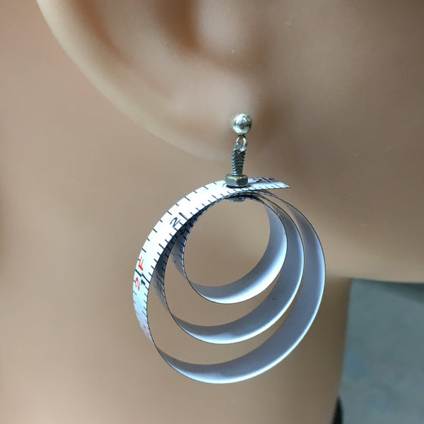 A wonderful flea market find inspired me to make these earrings based on a 1990's Nike ad (see blog).  Somewhat of a limited edition because that's what happens with found objects.  When they're gone, they are gone.  Made from vintage tape measures, micro-screws hold the three concentric loops of each earring together.  Charm:  1.5" length, 1.25" width (approx. 1 1/8" diameter)  Total length:  1.5"  Sterling Silver posts