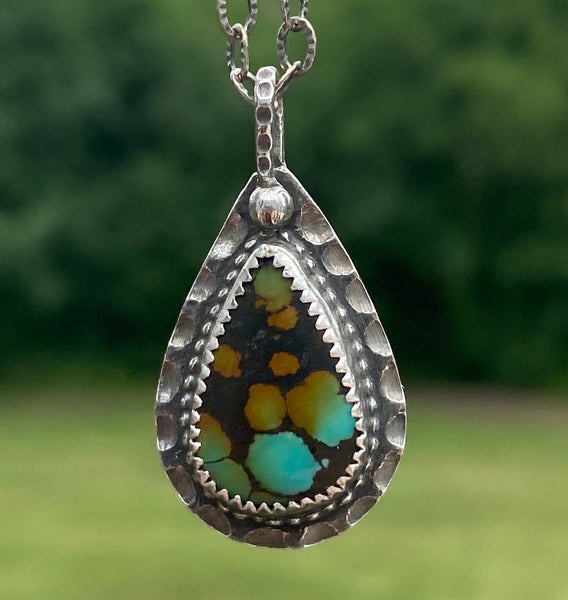 Offering wholeness, the 17 x 10mm pear-shaped Hubei Turquoise has a beautiful color palette of orange, green and blue organic shaped spots on a black background.  It is set in texturized and patinated Sterling Silver.  Charm:  1.25"L x .75"W  Chain:  17" L, 2.8mm oxidized and patterned cable chain