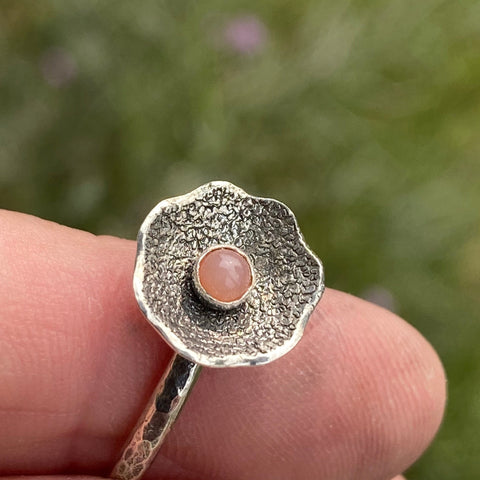 Textured and patinated Sterling Silver and a 3mm Peach Moonstone combine to create a delicate flower ring.  Peach Moonstone...such a powerful stone with much to offer.  A stone for wishing and hoping, it recognizes the difference between need and want on a universal level.  Size 7.75