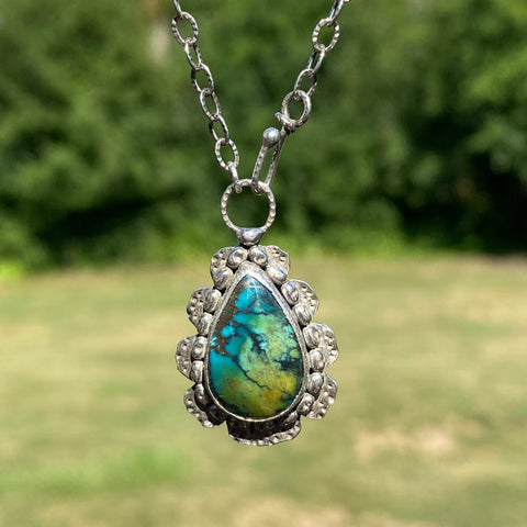 Offering wholeness, the 17 x 10mm pear-shaped Hubei Turquoise has a beautiful color palette of orange, green and blue organic shaped spots on a black background. &nbsp;It is set in texturized and patinated Sterling Silver.

Charm: &nbsp;1.25"L x .75"W

Chain: &nbsp;17" L, 2.8mm oxidized and patterned cable chain