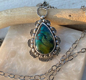 Blue and green are the predominant colors of this beautiful teardrop shaped Hubei Turquoise stone.  Measuring 17 x 11mm it is set in texturized layers of Sterling Sterling Silver.  Charm:  1.25L x .75W  Chain: 20" oxidized, patterned 2.8mm cable chain and handmade hook clasp.