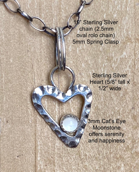 A 3mm Cat's Eye Moonstone nests in a textured Sterling Silver heart.  This semi-precious gemstone is said to offer serenity and happiness.  Charm:  5/8" x 1/4" Sterling Silver heart with a 3mm Cat's Eye Moonstone  Chain:  19" Sterling Silver 2.5mm oval rollo chain