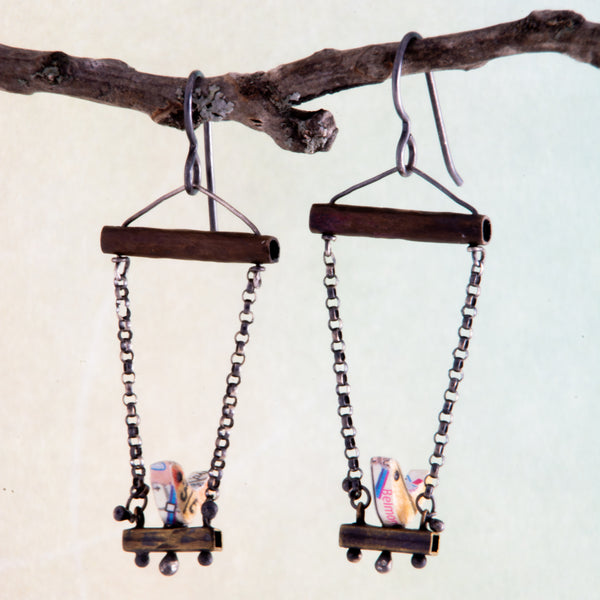 Who doesn't love hanging with a friend, sitting side by side as conversations meander from shoes to the meaning of life?  These handmade earrings feature tiny birds made using vintage rulers are edged in maps and have 1mm Black Spinel eyes.  The swing set is made with copper, brass, Sterling Silver and Argentium®.