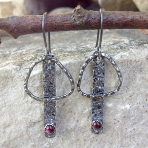 These handmade earrings are patinated to emphasize the hand texturing created on Sterling Silver and Argentium™ metals.  A 3mm, bezel-set Pink Tourmaline is the finishing touch.  20 gauge Argentium™ ear wires  Total Length:  2" from the top of the ear wires to the bottom of the charm.  Charm size:    1 3/8" long x 3/4" wide  Pink Tourmaline can help with understanding love.