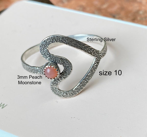 Textured and patinated Sterling Silver and a 3mm Peach Moonstone combine to create a delicate heart shaped ring.  Peach Moonstone...such a powerful stone with much to offer.  A stone for wishing and hoping, it recognizes the difference between need and want on a universal level.  Size 10