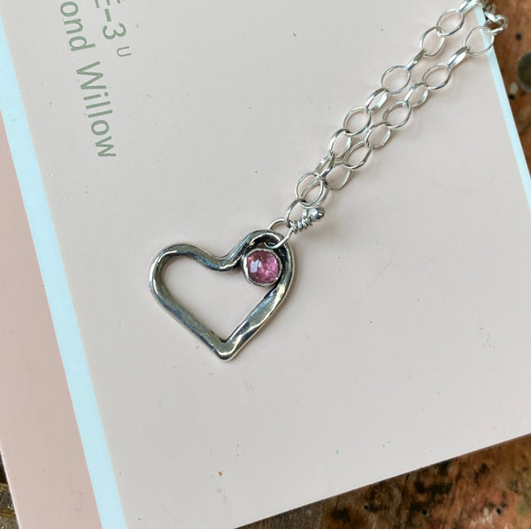 A 3mm Pink Tourmaline embellishes the Sterling Silver heart.  Pink Tourmaline offers joy, enthusiasm and a chance to trust in the power of love.  Charm:  1/2" long x 1/2" wide  Chain:   20" Sterling Silver 2.5mm oval rolo chain